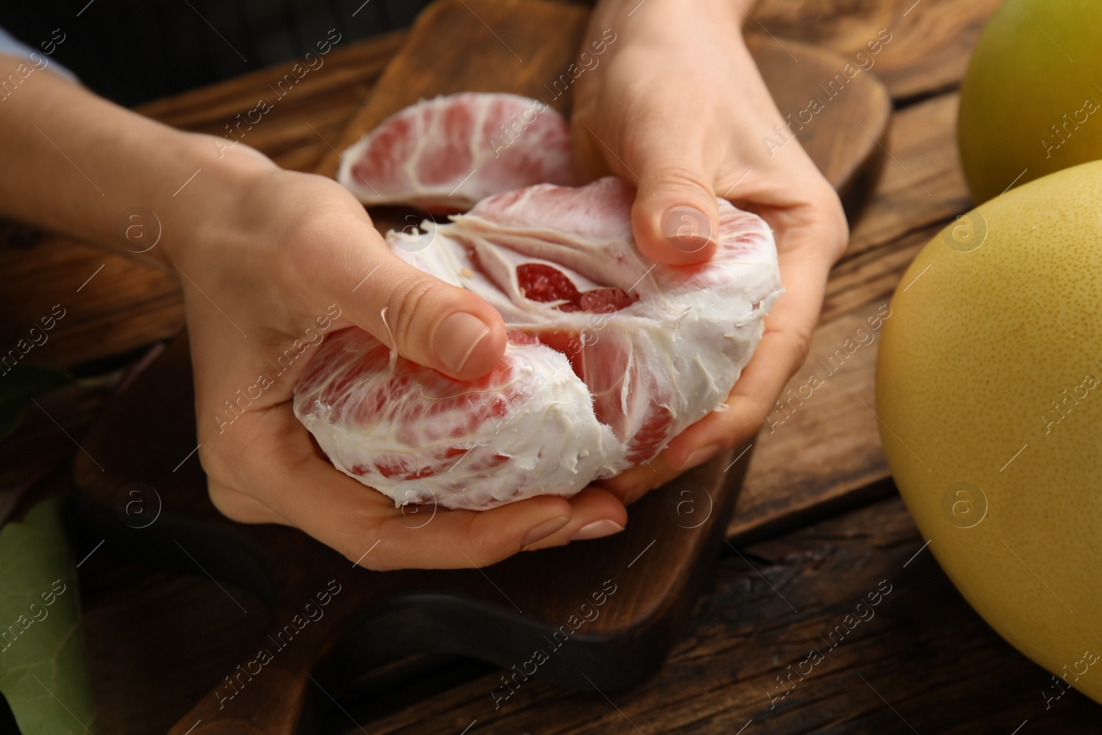 Photo of Woman with tasty red pomelo at wooden table, closeup