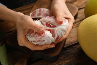 Photo of Woman with tasty red pomelo at wooden table, closeup