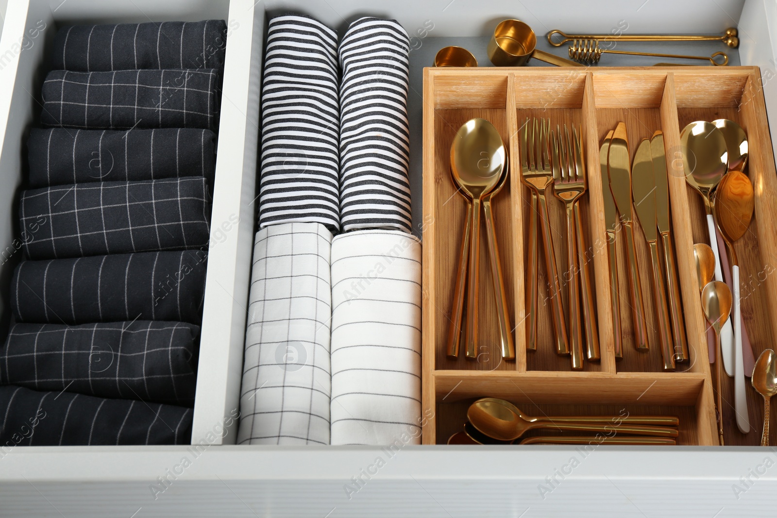 Photo of Open drawer with different utensils and folded towels. Order in kitchen