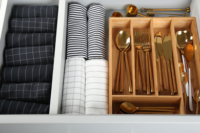 Photo of Open drawer with different utensils and folded towels. Order in kitchen