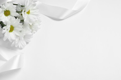 Beautiful chrysanthemum flowers and ribbon on white background, space for text. Funeral symbols