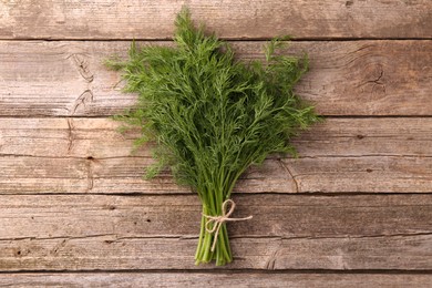 Photo of Bunch of fresh dill on wooden table, top view