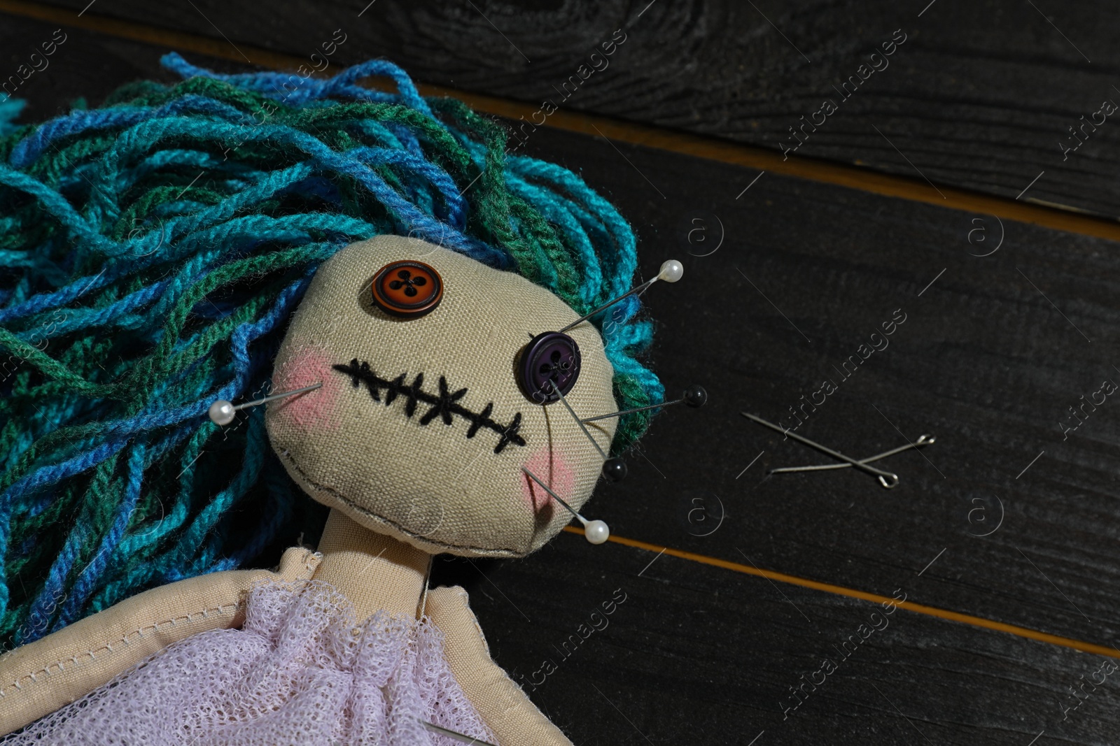 Photo of Female voodoo doll with pins on wooden background, closeup