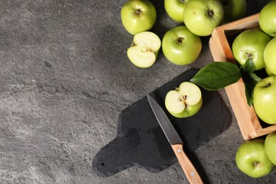 Photo of Ripe green apples, cutting board and knife on grey table, flat lay. Space for text