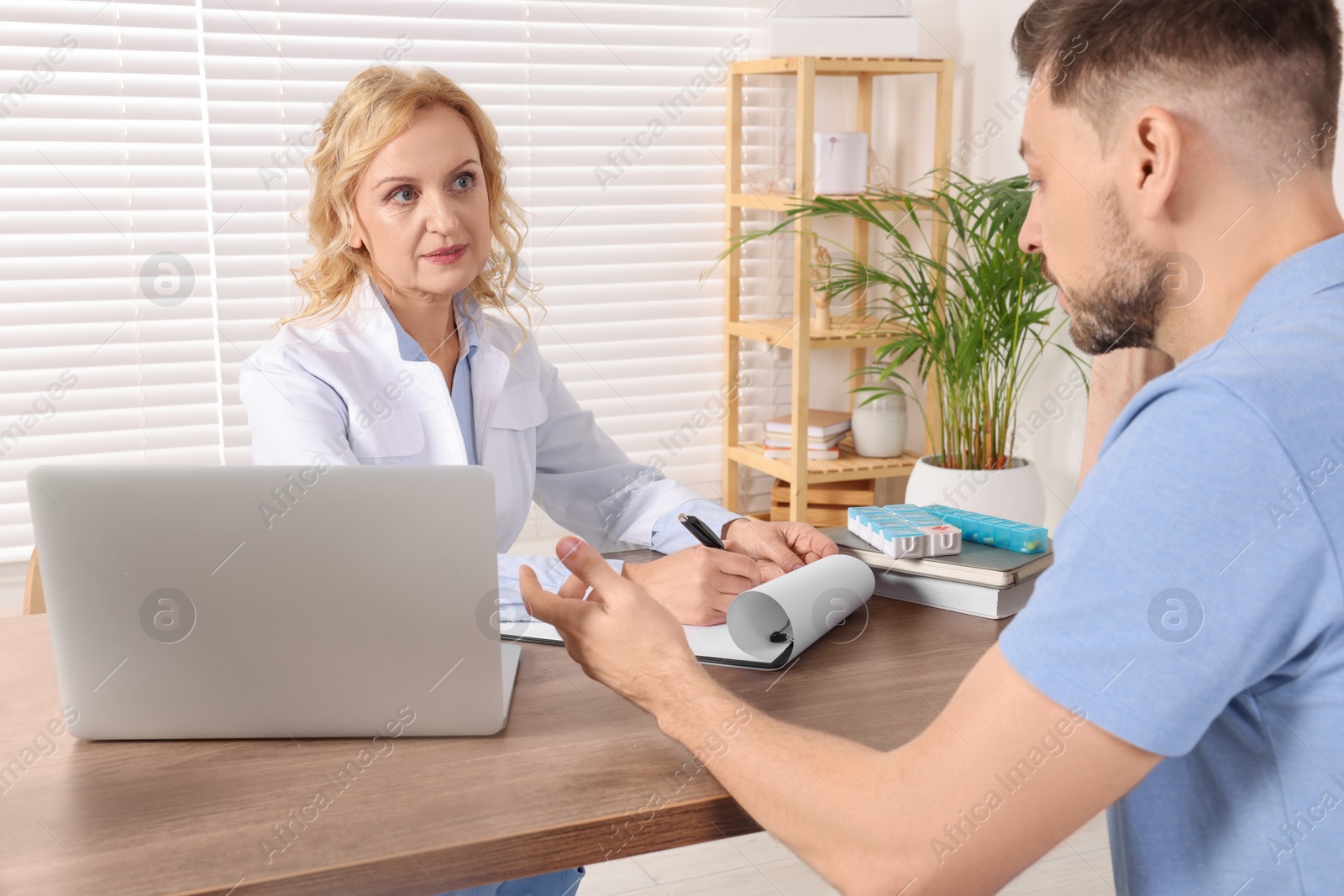 Photo of Doctor consulting patient at table in clinic