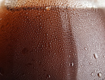 Photo of Glass of tasty refreshing cola with water drops, closeup