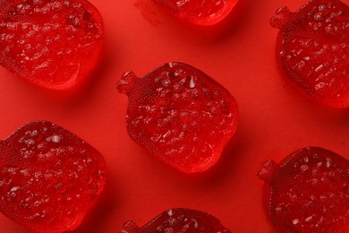 Photo of Delicious gummy pomegranate candies on red background, flat lay