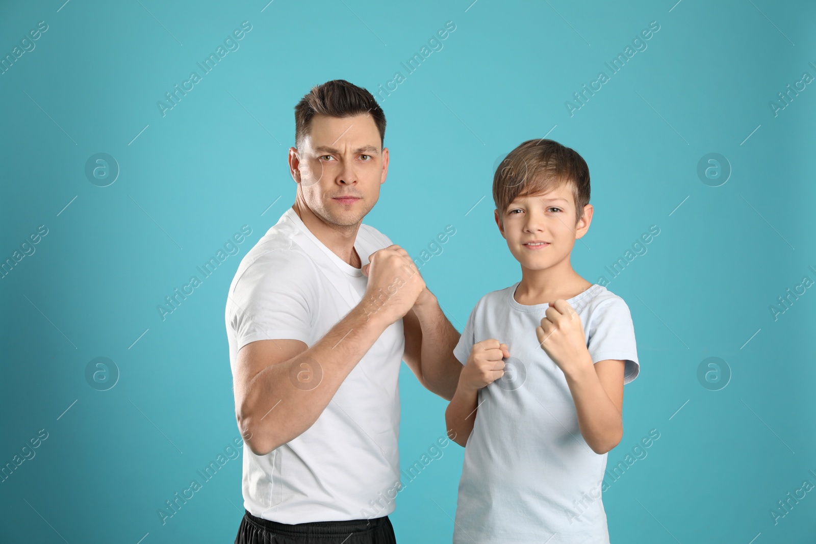 Photo of Portrait of sporty dad and his son on color background