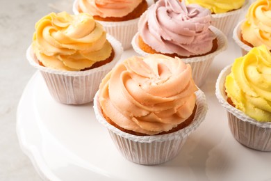 Photo of Tasty cupcakes with cream on white stand, closeup
