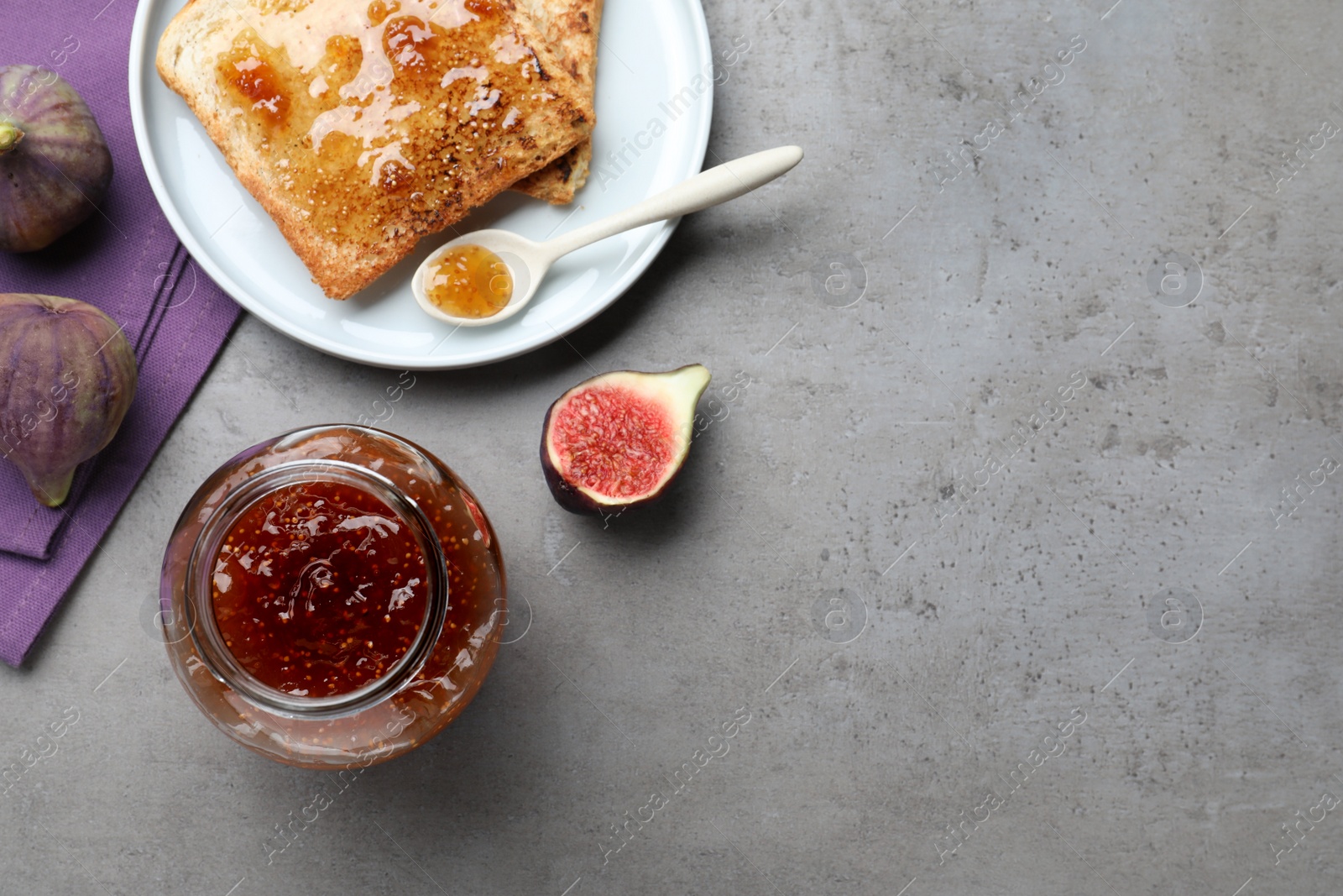 Photo of Delicious fig jam and toasts on grey table, flat lay. Space for text