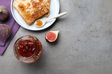 Photo of Delicious fig jam and toasts on grey table, flat lay. Space for text