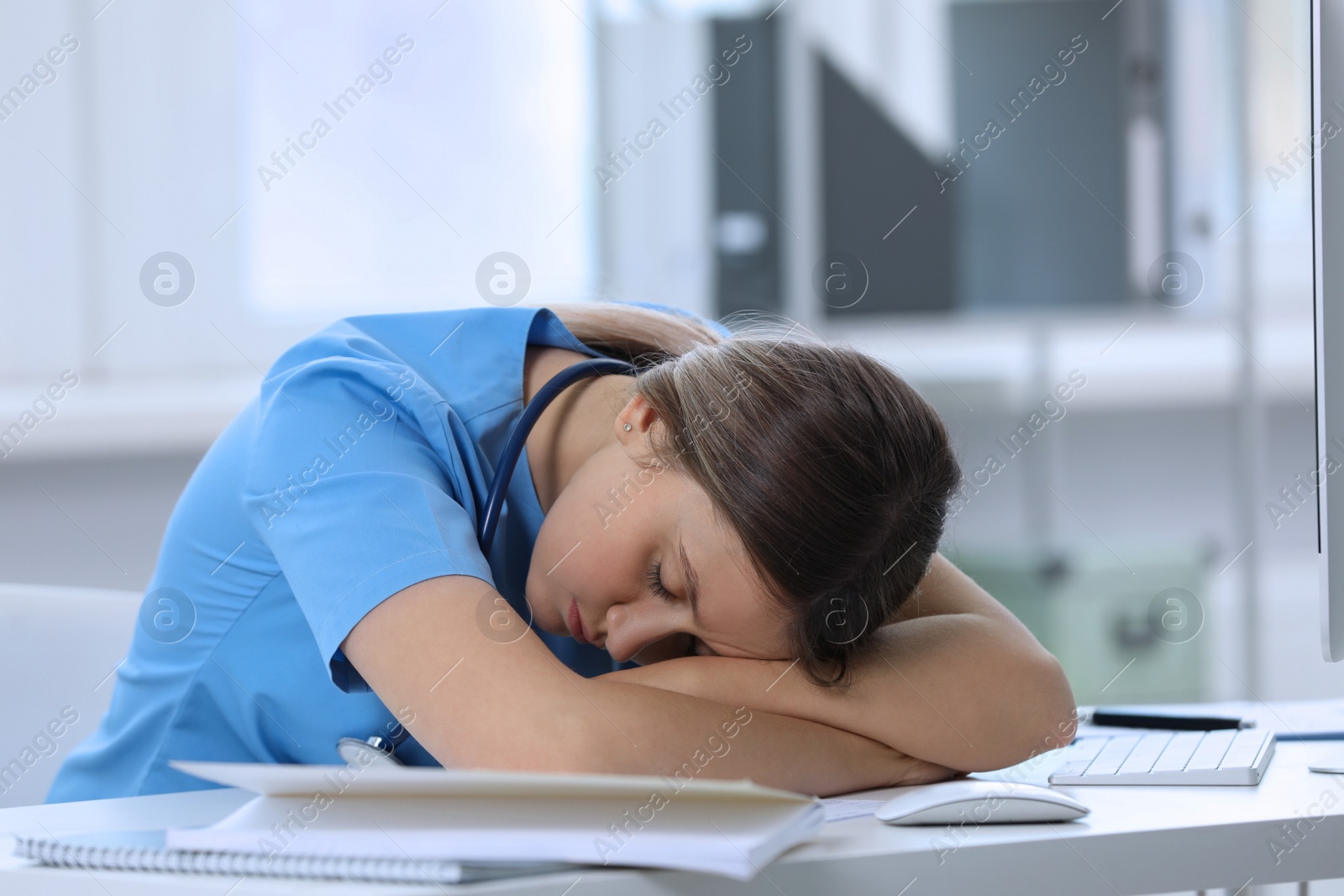 Photo of Exhausted doctor sleeping at workplace in hospital