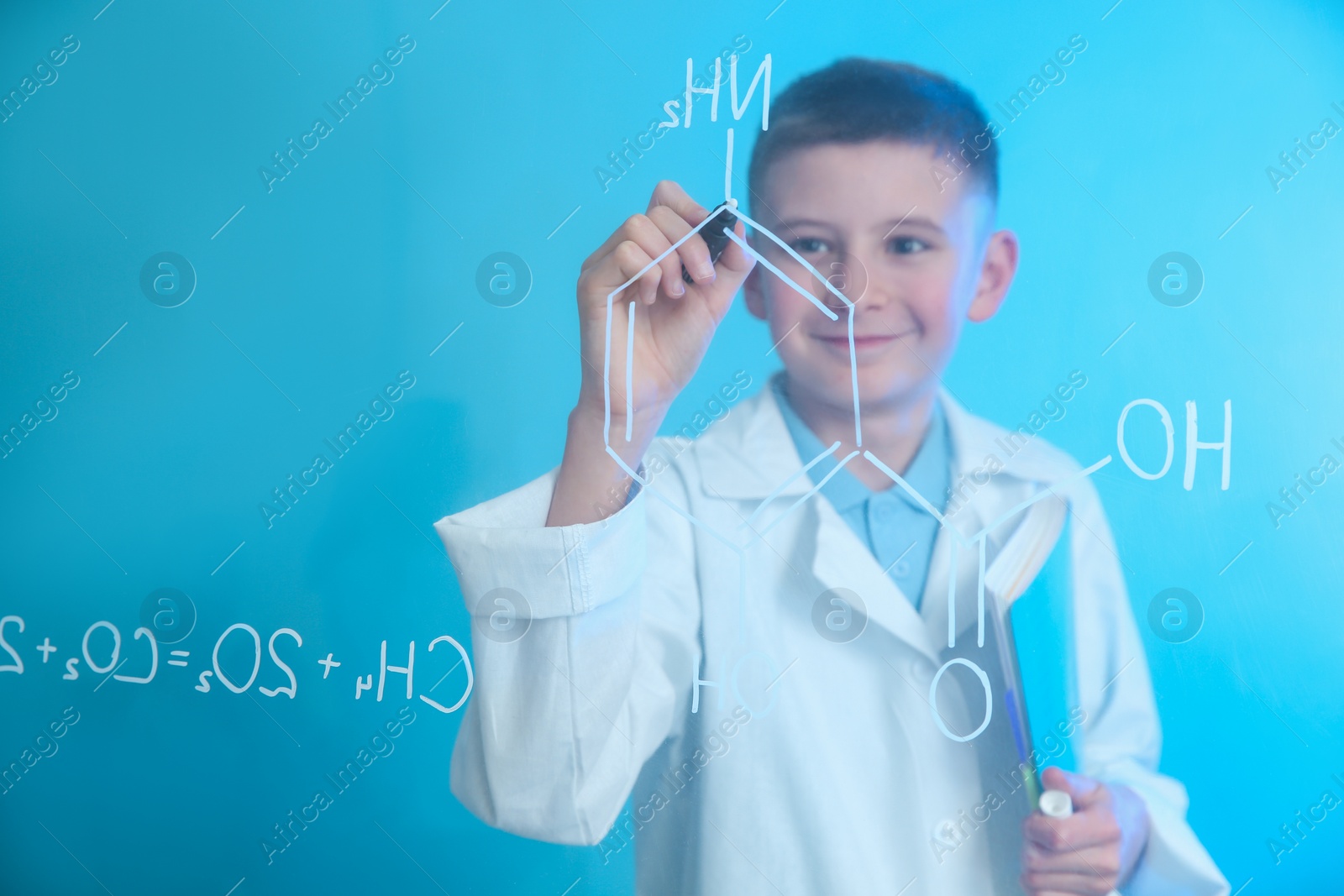 Photo of Schoolboy writing chemistry formula on glass board against color background. Space for text