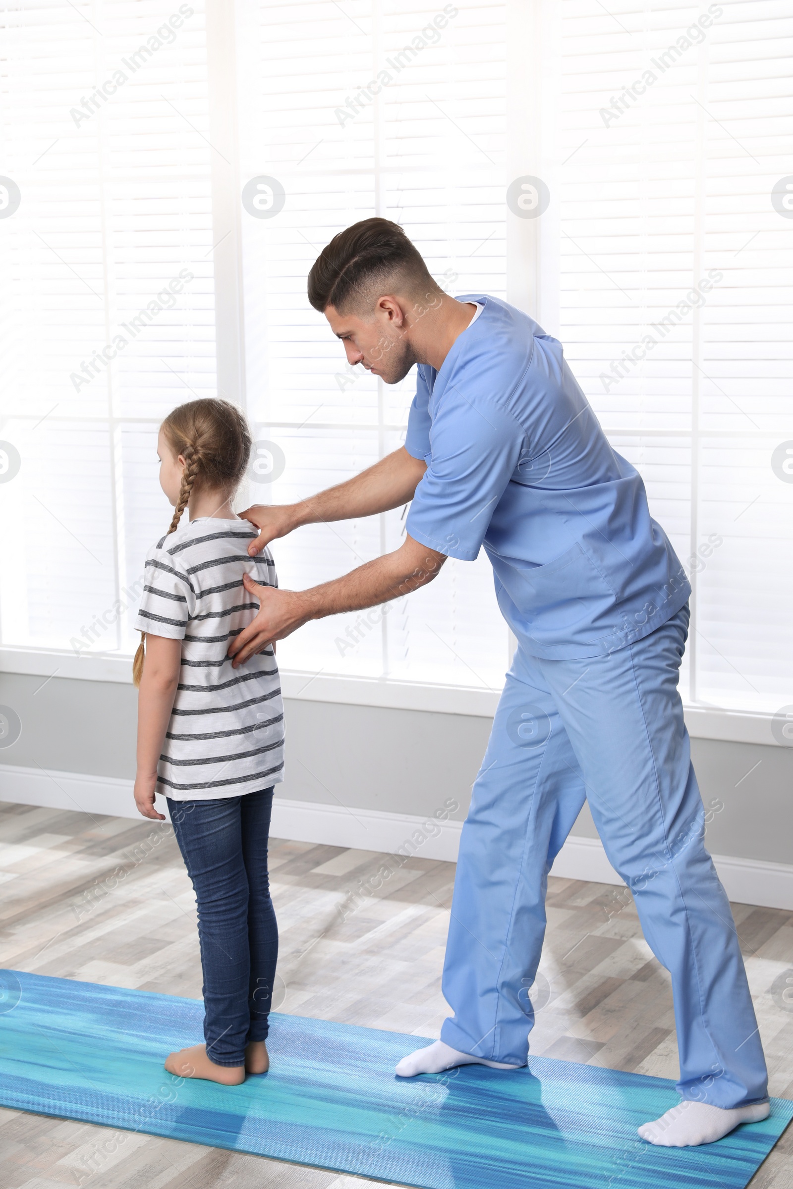 Photo of Orthopedist examining child's back in clinic. Scoliosis treatment