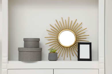 Photo of Grey decorative boxes, houseplant, mirror and frame on shelving unit