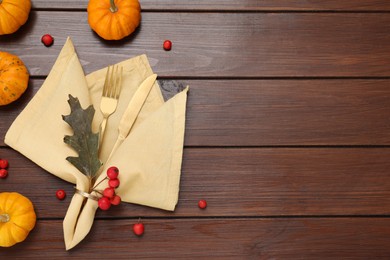 Photo of Cutlery, napkin and autumn decoration on wooden background, flat lay with space for text. Table setting