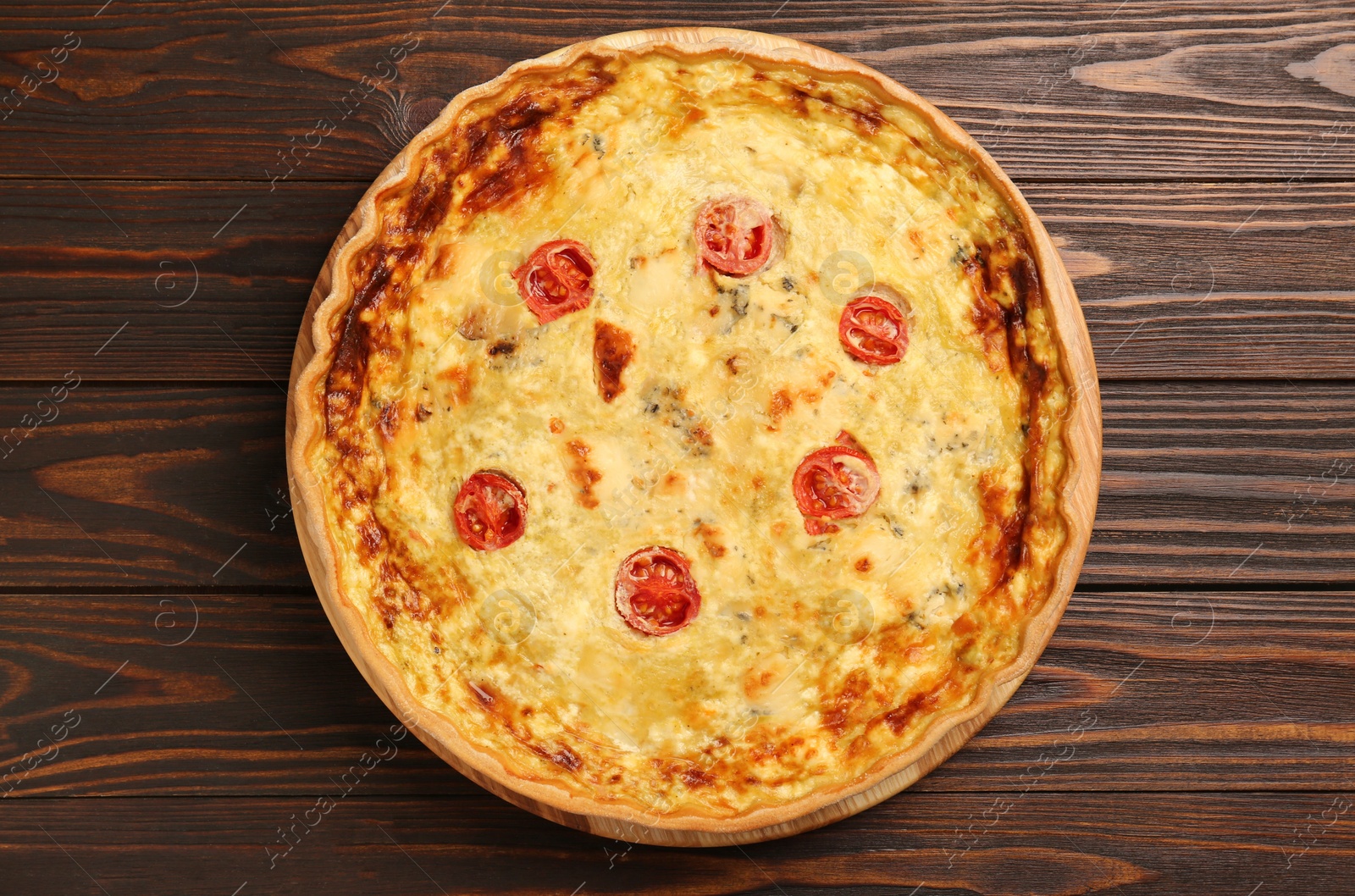 Photo of Delicious quiche with cheese and tomatoes on wooden table, top view