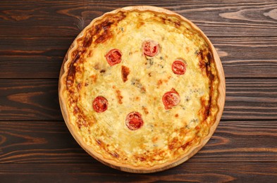 Photo of Delicious quiche with cheese and tomatoes on wooden table, top view