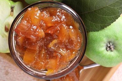 Photo of Glass jar of delicious apple jam and fresh fruits on light table, top view