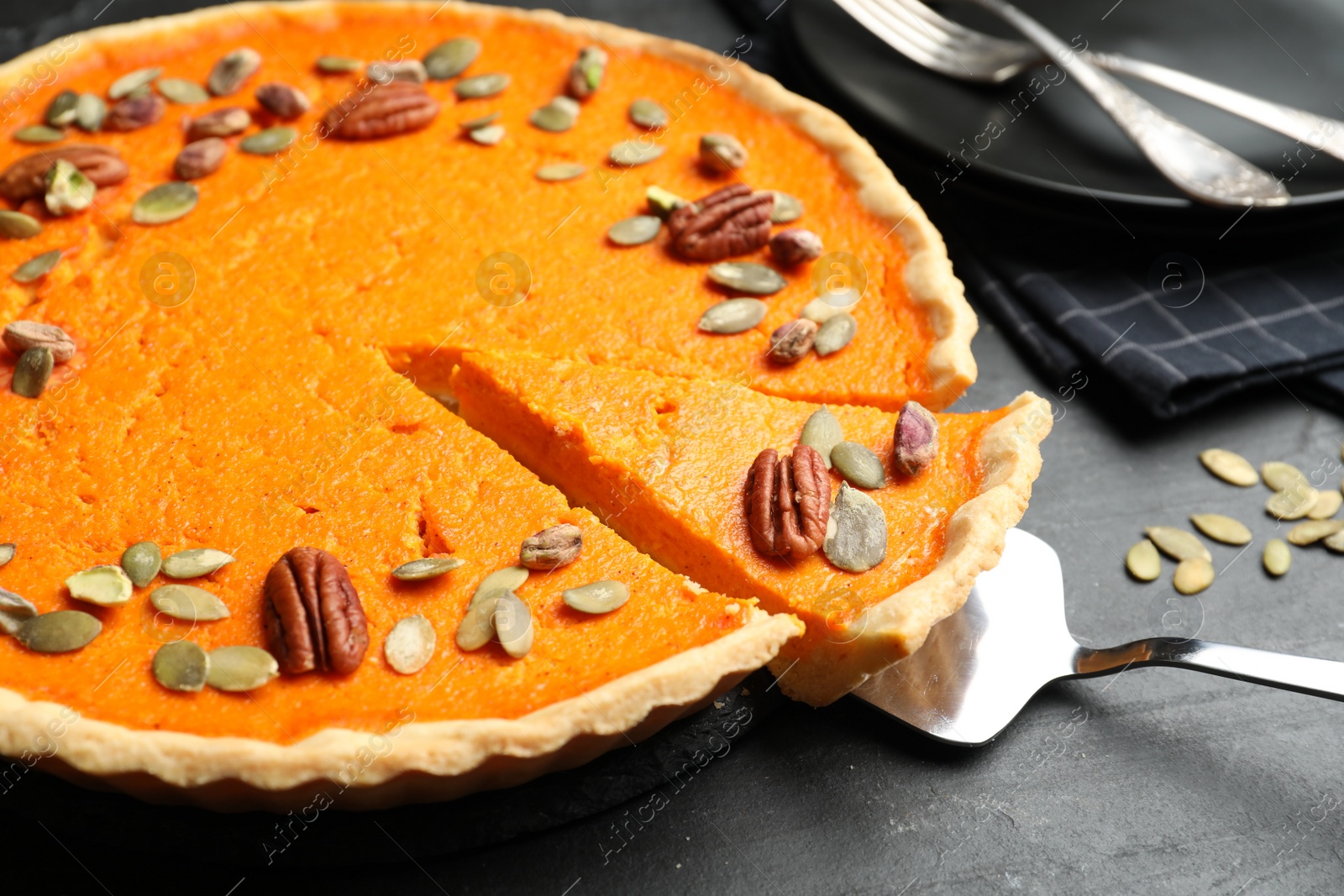 Photo of Delicious homemade pumpkin pie on black table, closeup