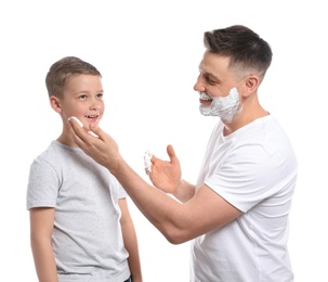 Dad applying shaving foam on son's face, white background