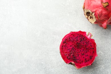 Photo of Delicious cut and whole red pitahaya fruits on light grey table, flat lay. Space for text