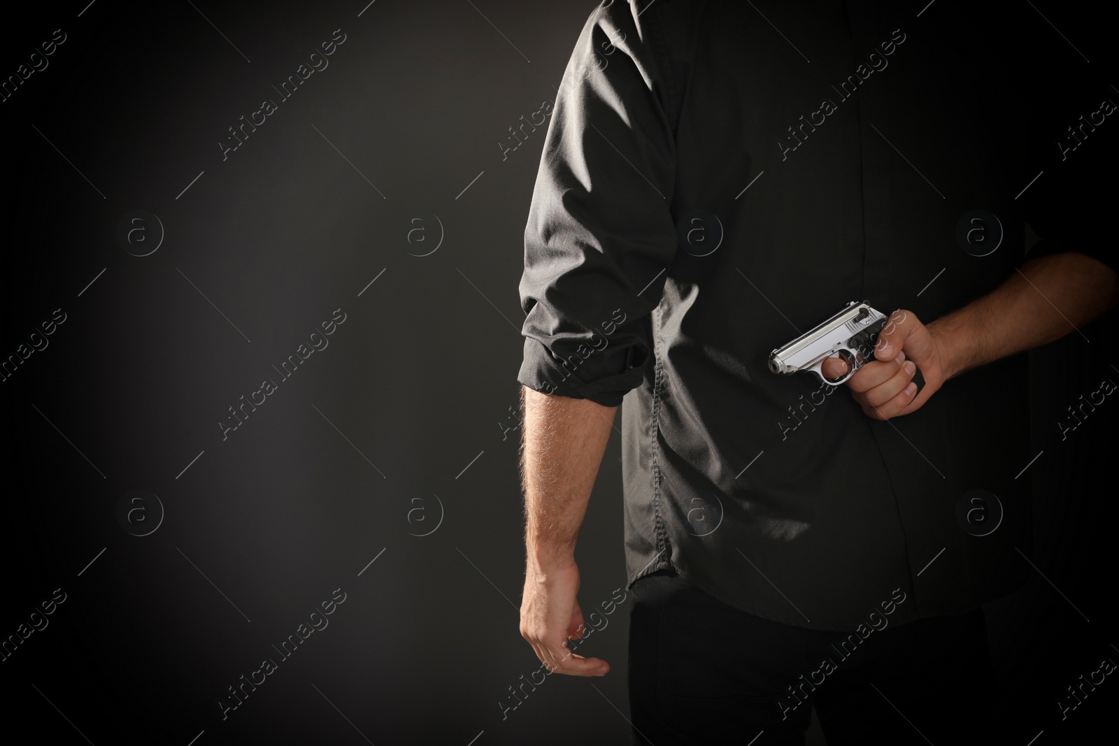 Photo of Professional killer with gun on black background, closeup. Space for text