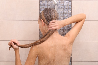 Young woman washing hair in shower at home