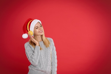 Photo of Happy woman with headphones on red background, space for text. Christmas music