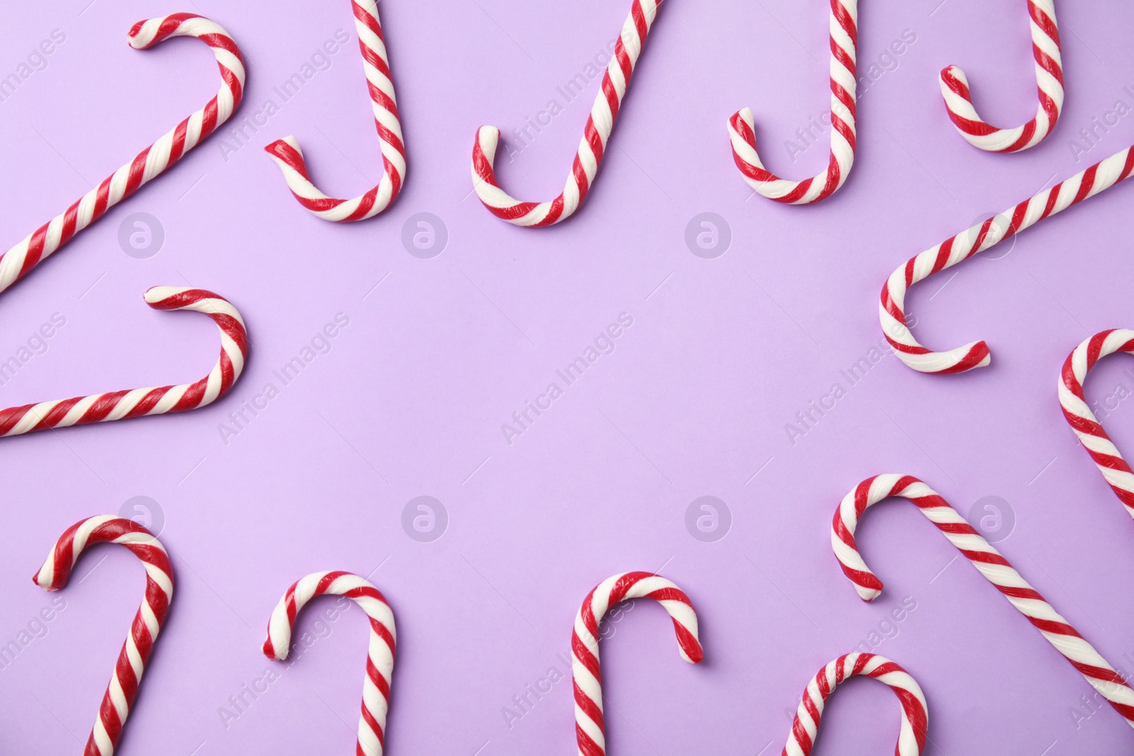 Photo of Flat lay composition with candy canes on lilac background. Space for text