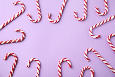 Photo of Flat lay composition with candy canes on lilac background. Space for text