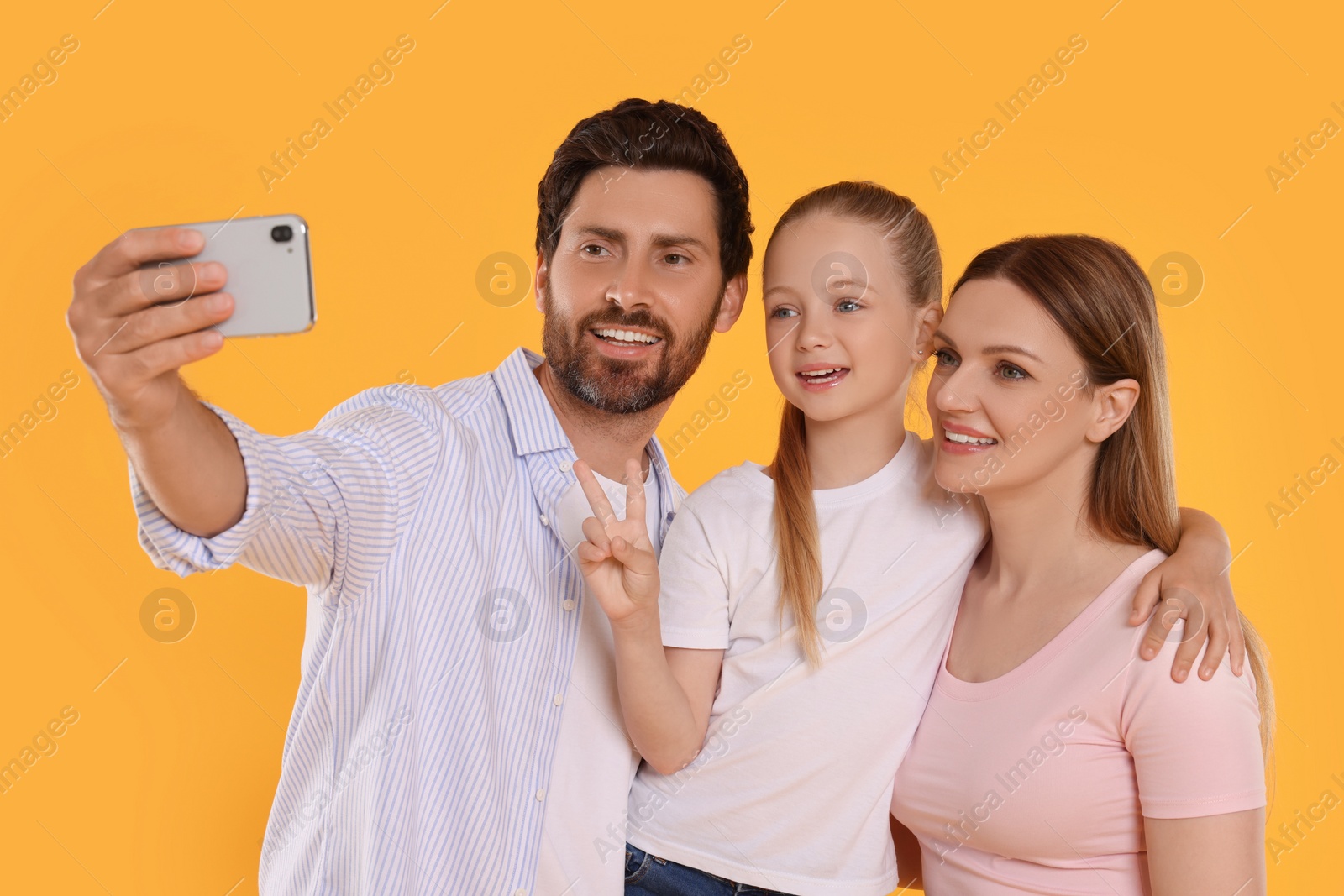 Photo of Happy family taking selfie on orange background