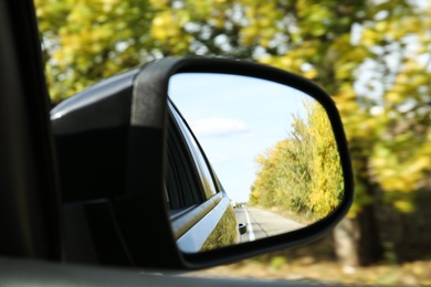 Photo of Closeup of car side rear view mirror on sunny day