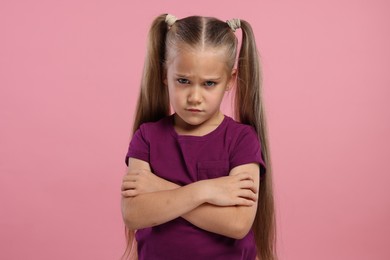 Photo of Resentful girl with crossed arms on pink background