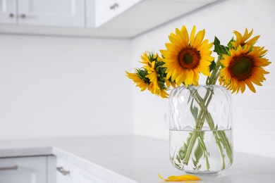 Bouquet of beautiful sunflowers on counter in kitchen. Space for text