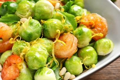 Bowl of delicious salad with Brussels sprouts and shrimps on table, closeup