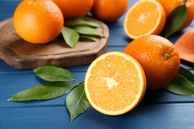 Photo of Delicious ripe oranges on blue wooden table