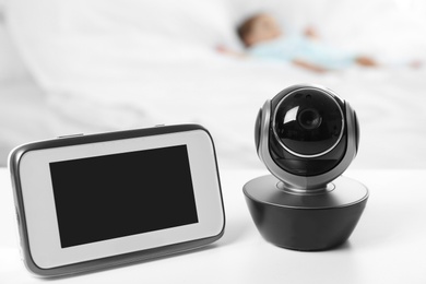 Baby monitor and camera on table near bed with child in room. Video nanny