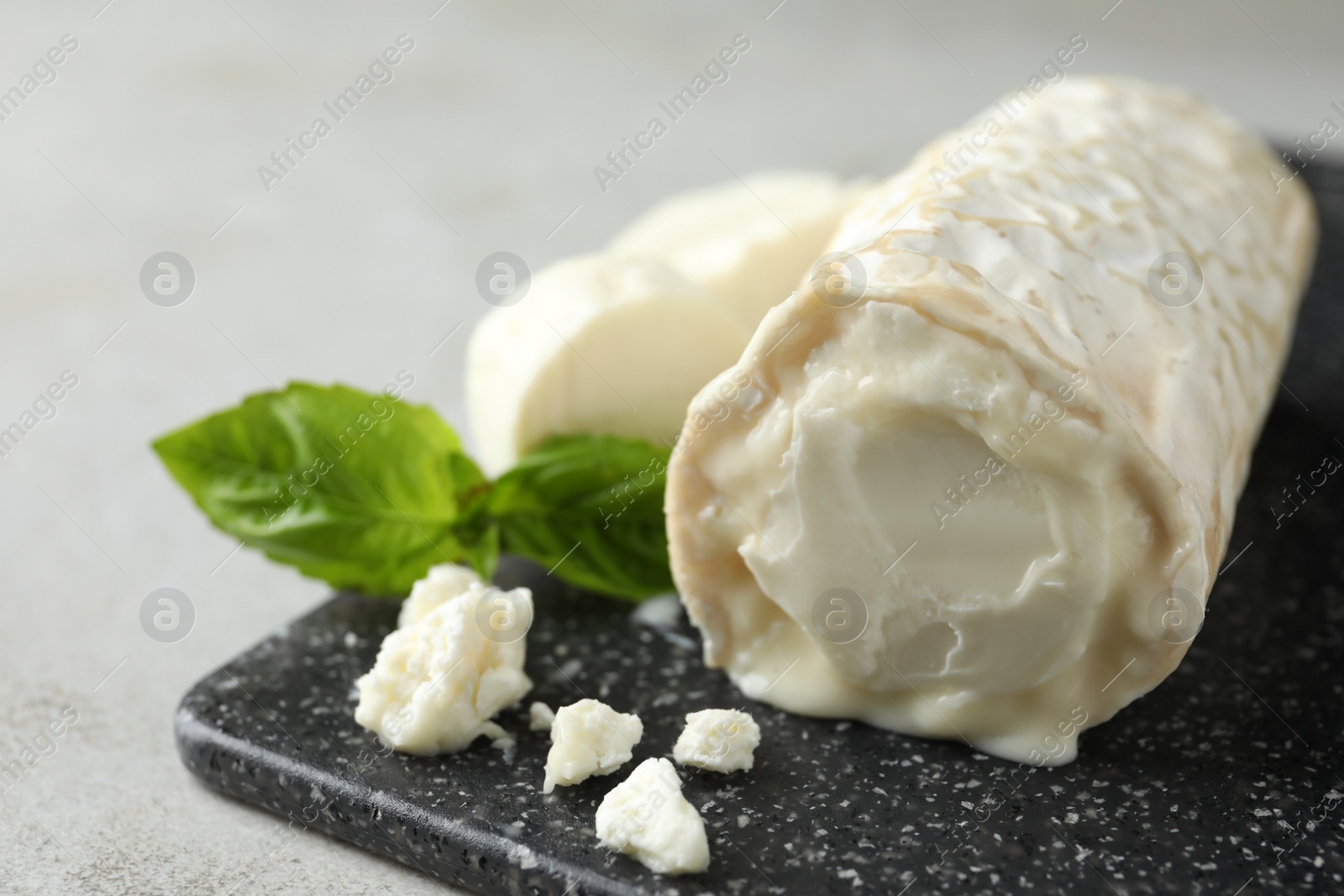 Photo of Delicious fresh goat cheese on black board, closeup