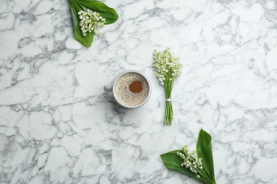 Flat lay composition with lily of the valley bouquets and coffee on marble background