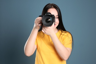 Female photographer with professional camera on color background