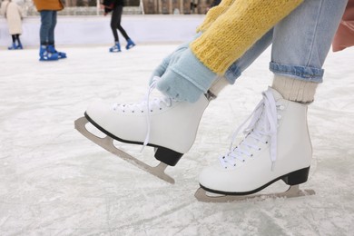 Photo of Woman lacing figure skates on ice rink, closeup