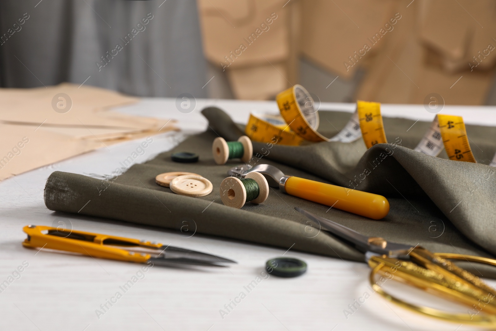 Photo of Set of sewing supplies and accessories with fabric on white wooden table indoors