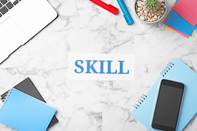 Photo of Workplace with word "Skill", mobile phone and stationery on light background. Business trainer concept