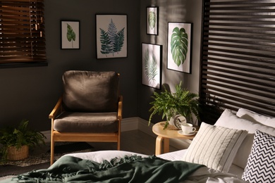 Comfortable bedroom with armchair and pictures on wall. Interior design