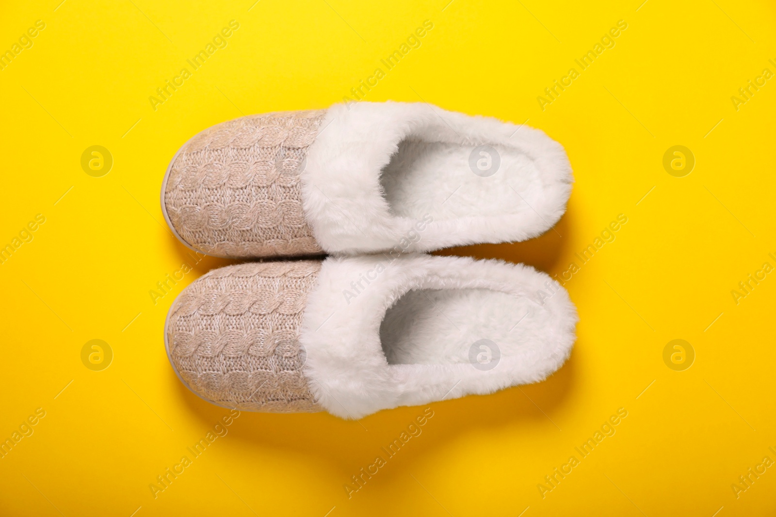 Photo of Pair of beautiful soft slippers on yellow background, top view