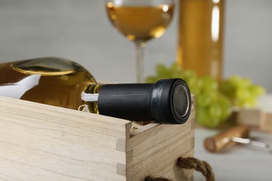 Photo of Wooden crate with bottle of wine on table, closeup