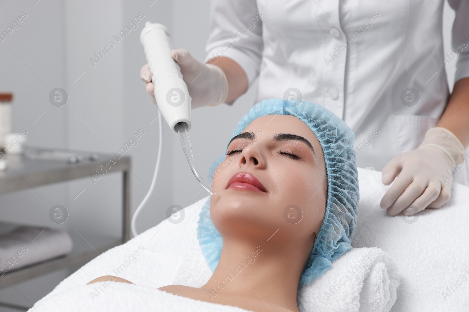 Photo of Young woman undergoing face rejuvenation procedure with darsonval in salon