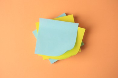 Blank paper notes on pale orange background, flat lay