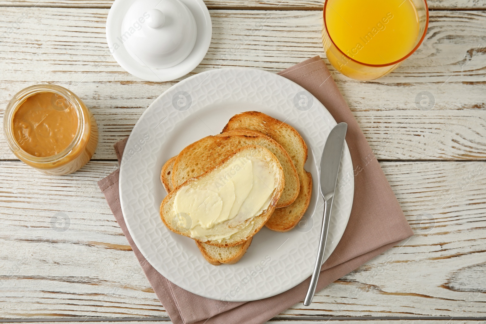 Photo of Tasty bread with butter served for breakfast on white wooden table, top view